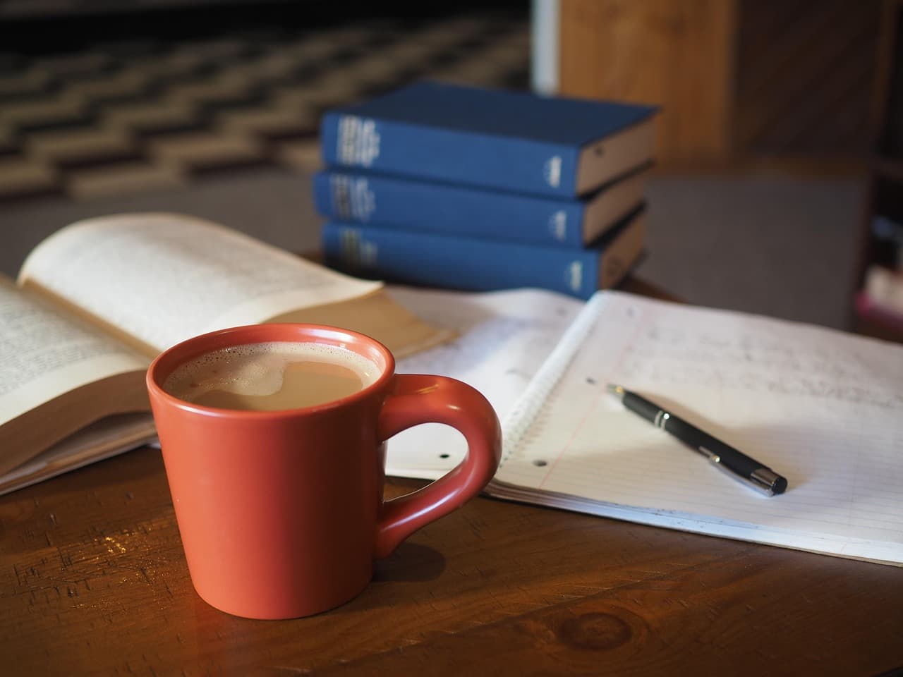 Notebook, glasses and a cup of coffee on a desk